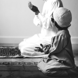 Muslim boy learning how to make Dua to Allah